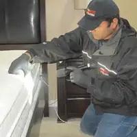 Bed bug inspection technician checking a mattress and bed frame for signs of infestation in Springfield, MO