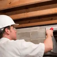 Termite inspection technician checking a basement wall and framing for termite activity in Springfield, MO